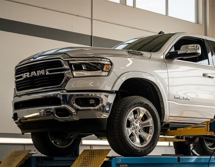 Domestic vehicle repair in Madison, WI at Torque Automotive. A white RAM pickup truck is elevated on a lift inside an auto repair shop, with sunlight streaming through large windows in the background.